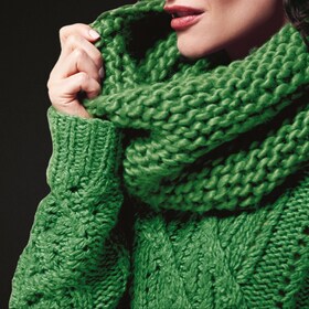 Moteris, besidžiaugianti namuose išskalbtu žaliu vilnoniu megztiniu ir šaliku